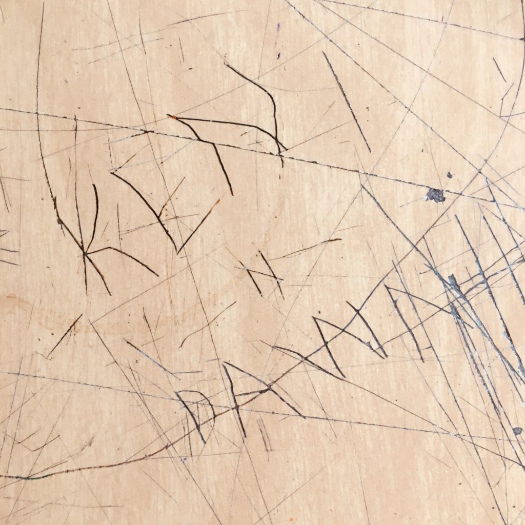 The words "Ken N Dawn" scratched into the desk surface.